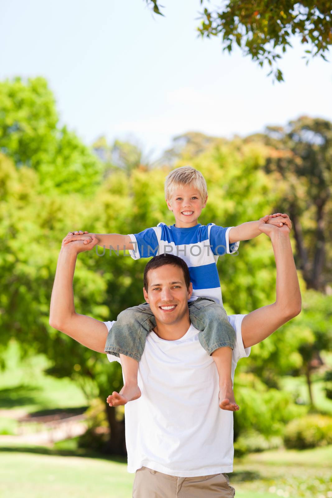 Man giving son a piggyback in a park by Wavebreakmedia