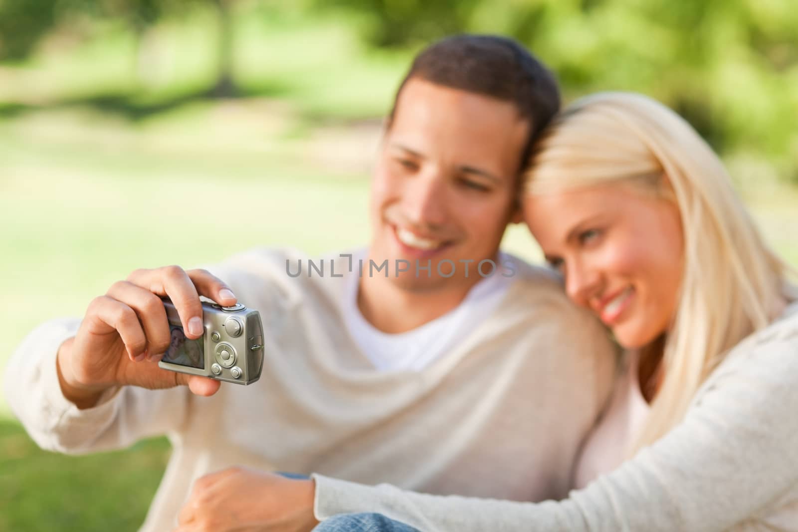 Young couple taking a photo of themselves during the summer in a park