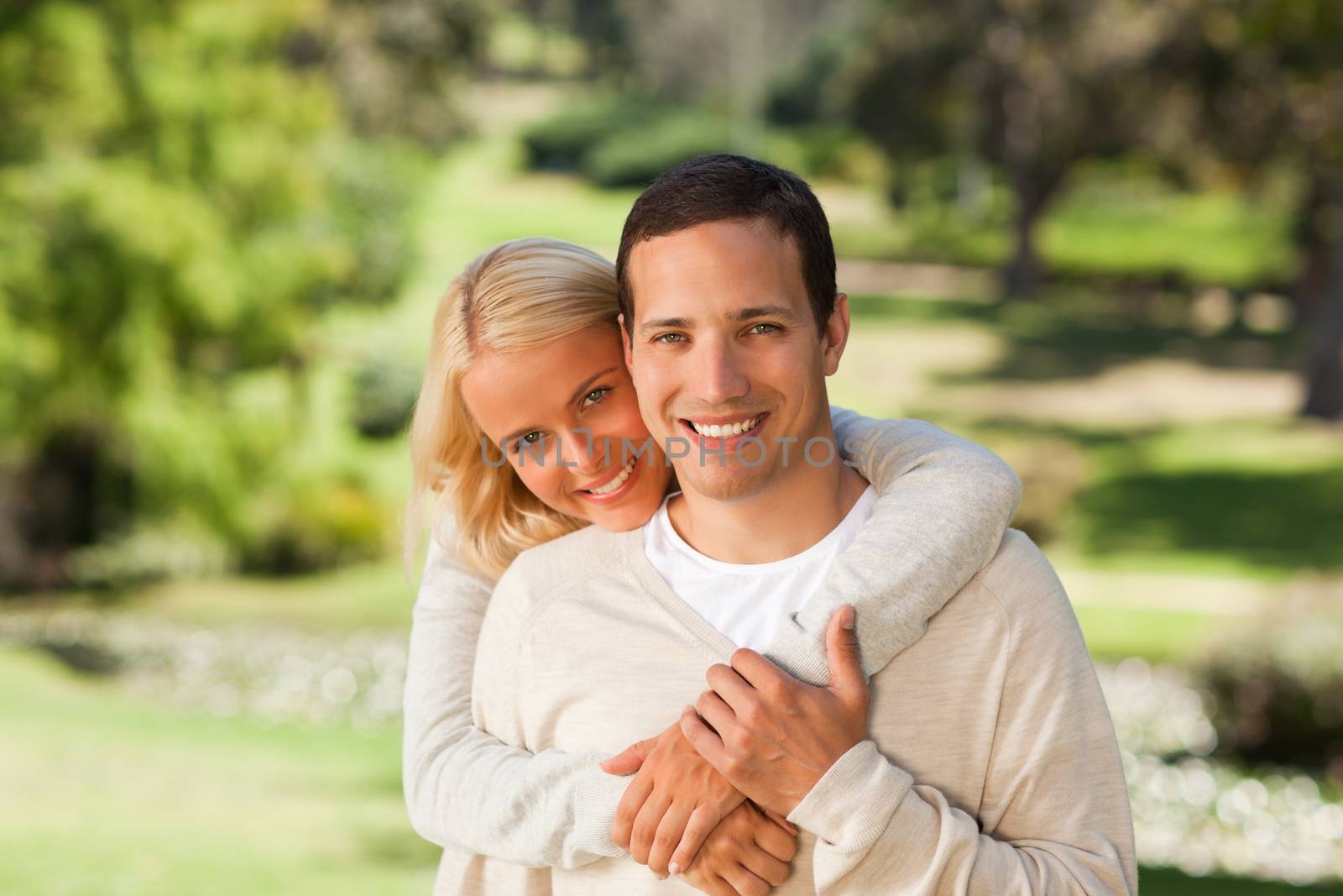 Woman hugging her boyfriend in the park during the summer 