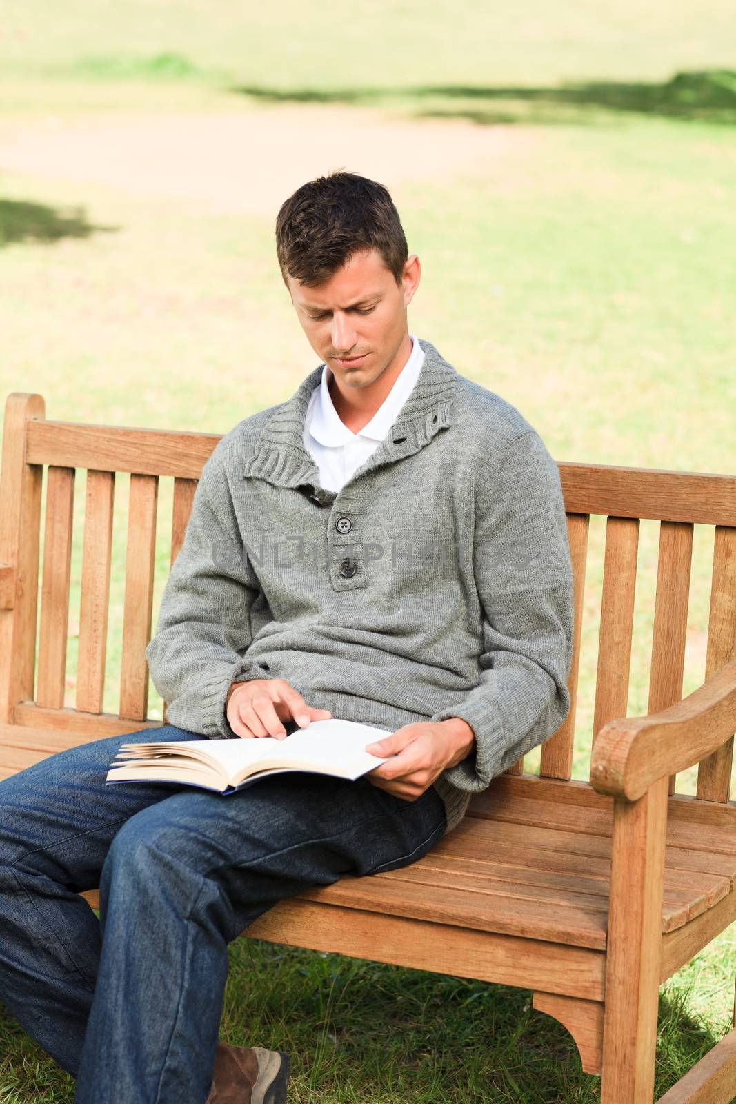 Man reading his book on the bench by Wavebreakmedia
