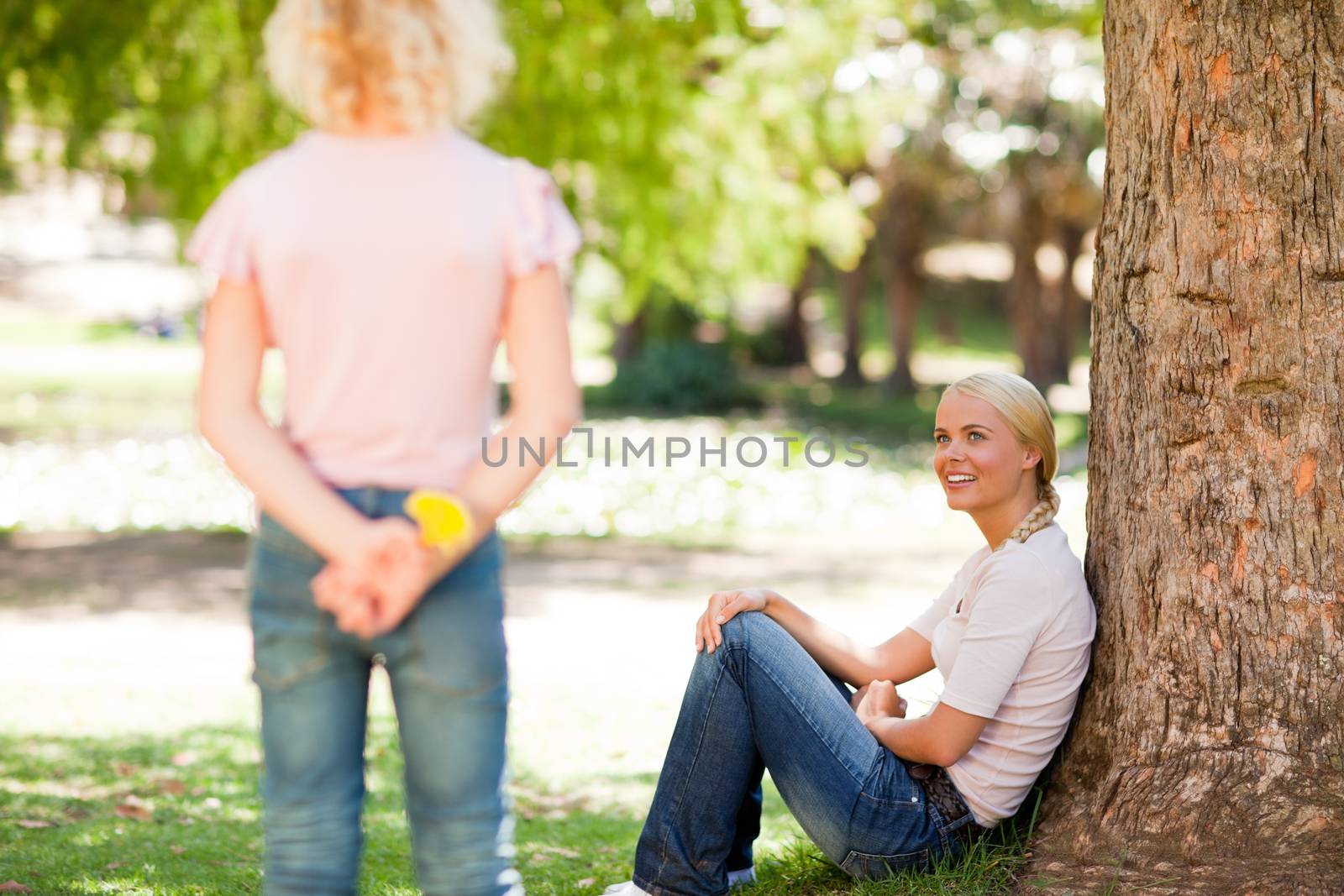 Daughter offering a flower to her mother in a park during the summer 