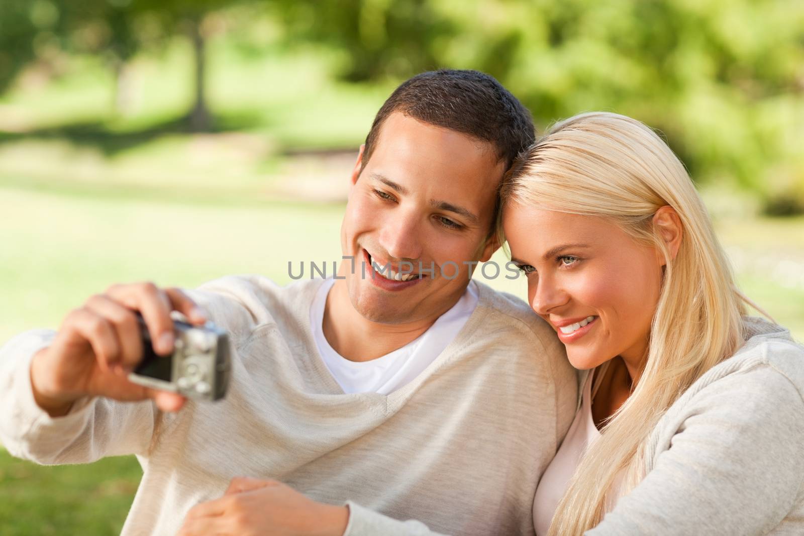 Young couple taking a photo of themselves in a park during the summer 