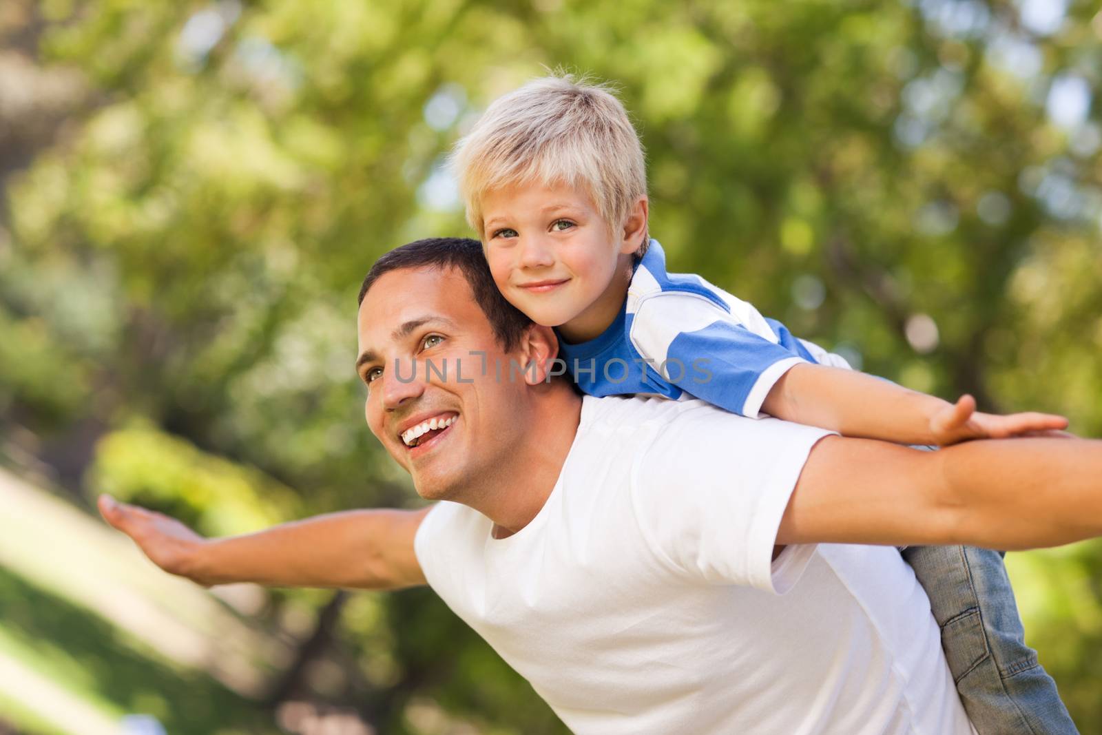 Son playing with his father in the park during the summer 