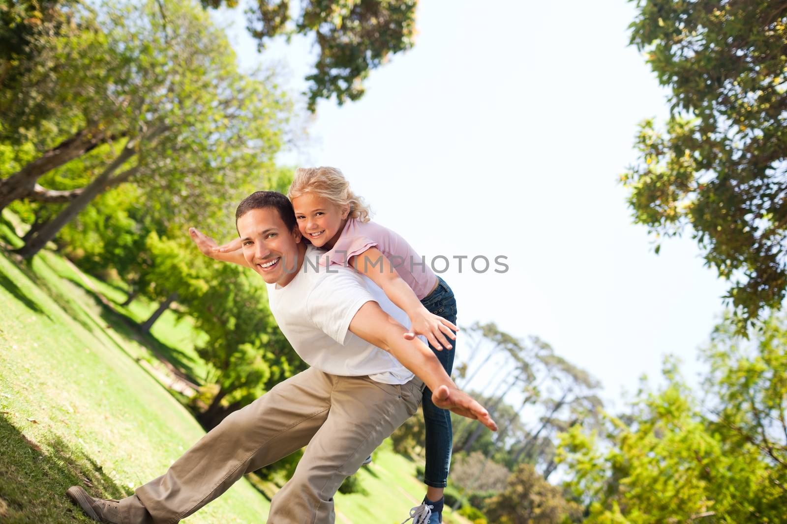 Little girl playing with her father in the park during the summer 