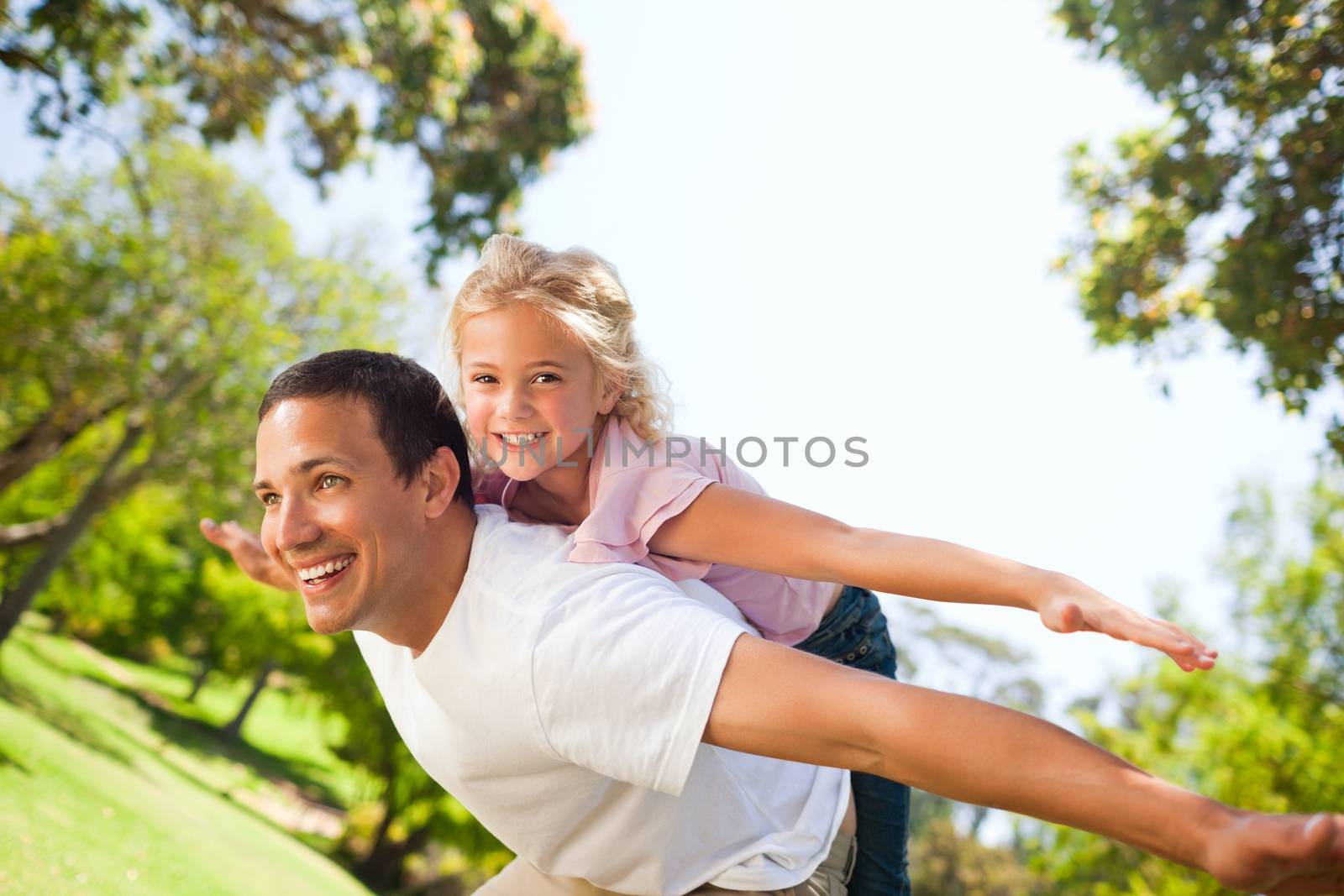 Father playing with his daughter in the park during the summer 