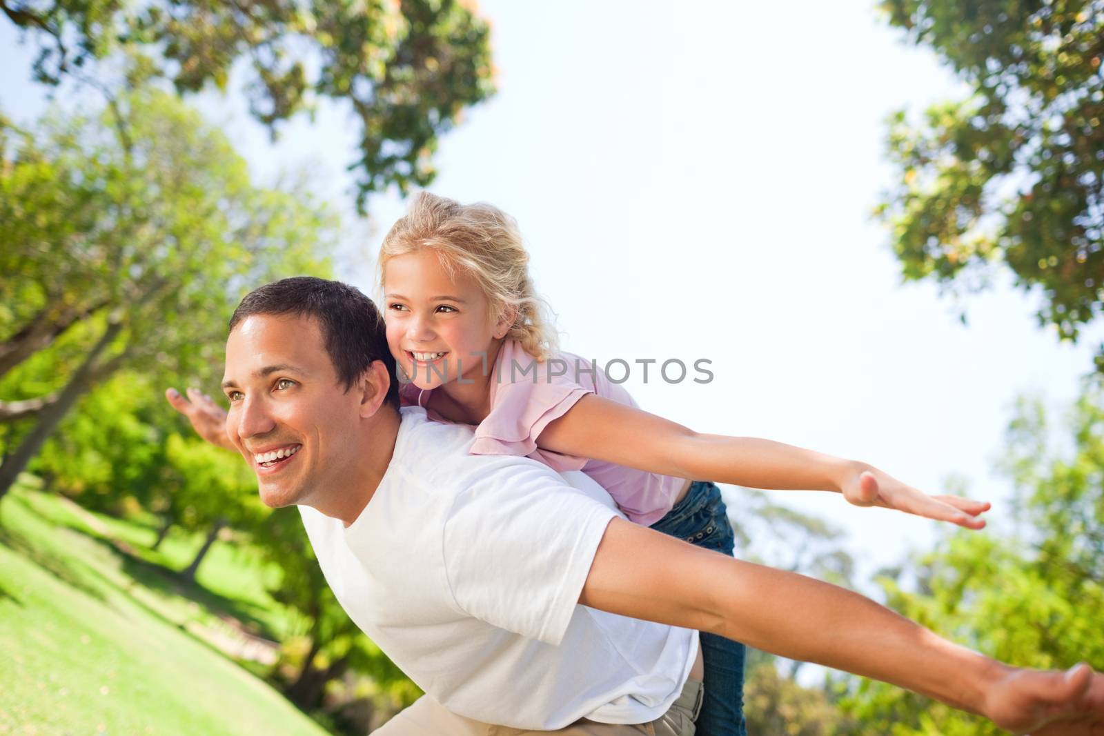 Father playing with his daughter in the park during the summer 