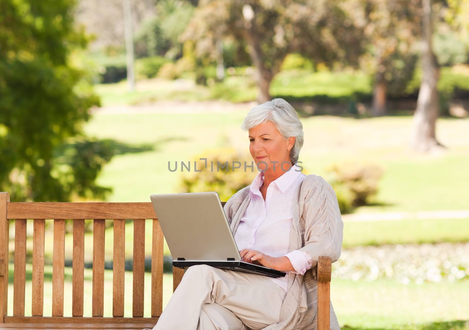 Retired woman working on her laptop during the summer 