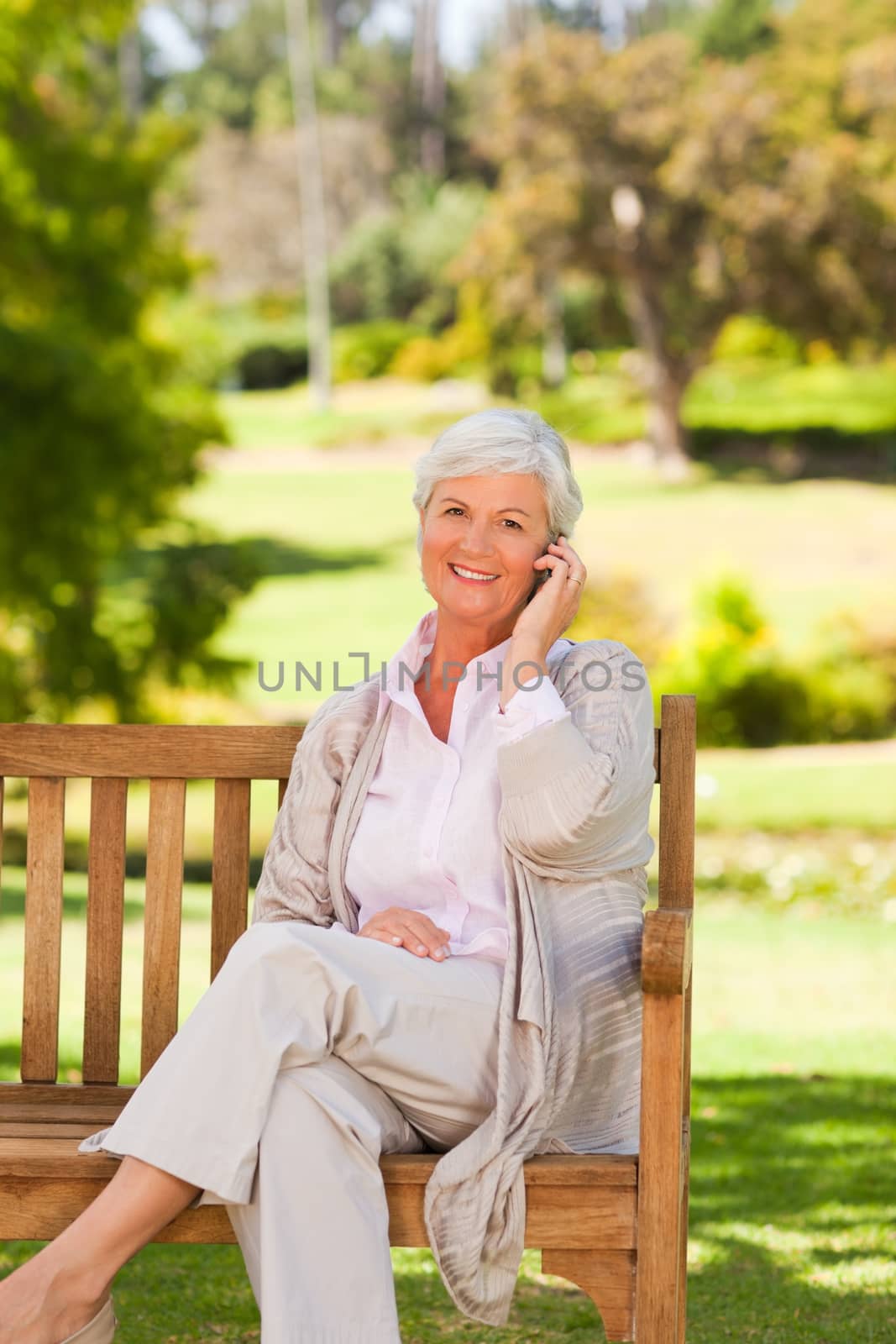 Elderly woman on a phone in a park by Wavebreakmedia