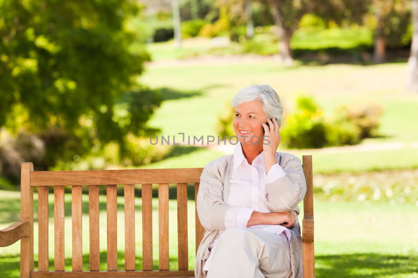 Elderly woman on a phone in a park during the summer 
