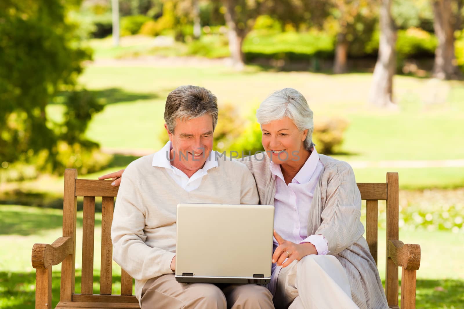 Couple working on their laptop sitting in the park by Wavebreakmedia