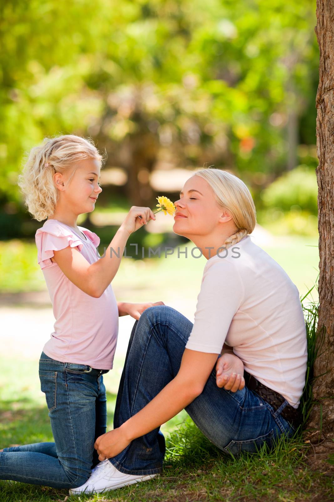 Mother and her daughter smelling a flower by Wavebreakmedia