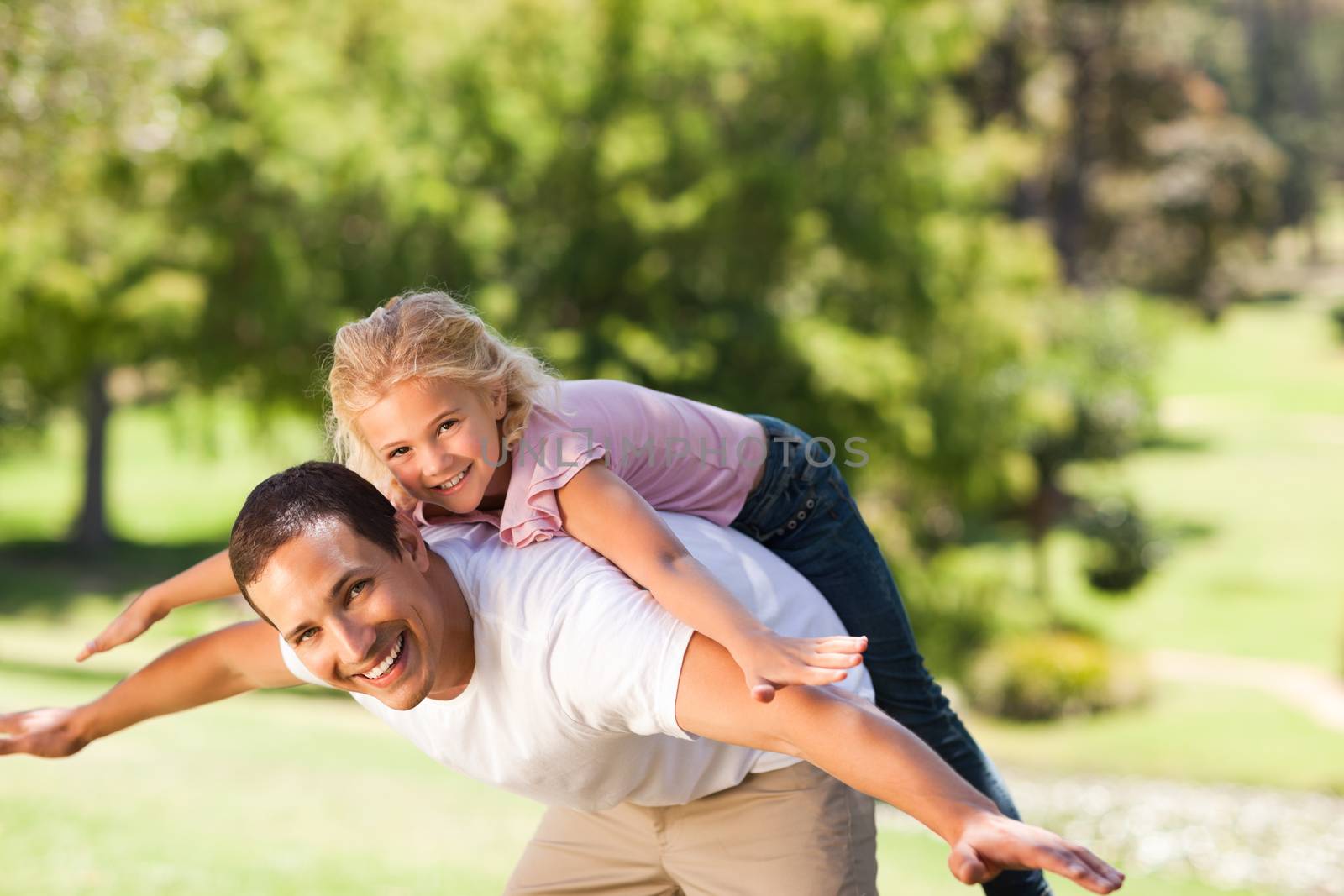 Little girl playing with her father in the park during the summer 