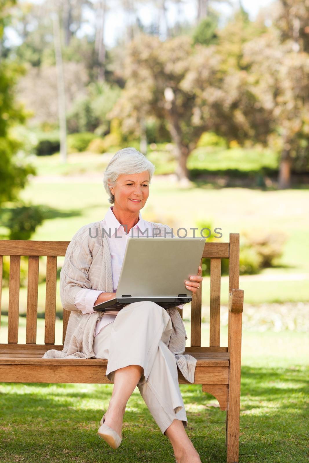 Retired woman working on her laptop during the summer  by Wavebreakmedia