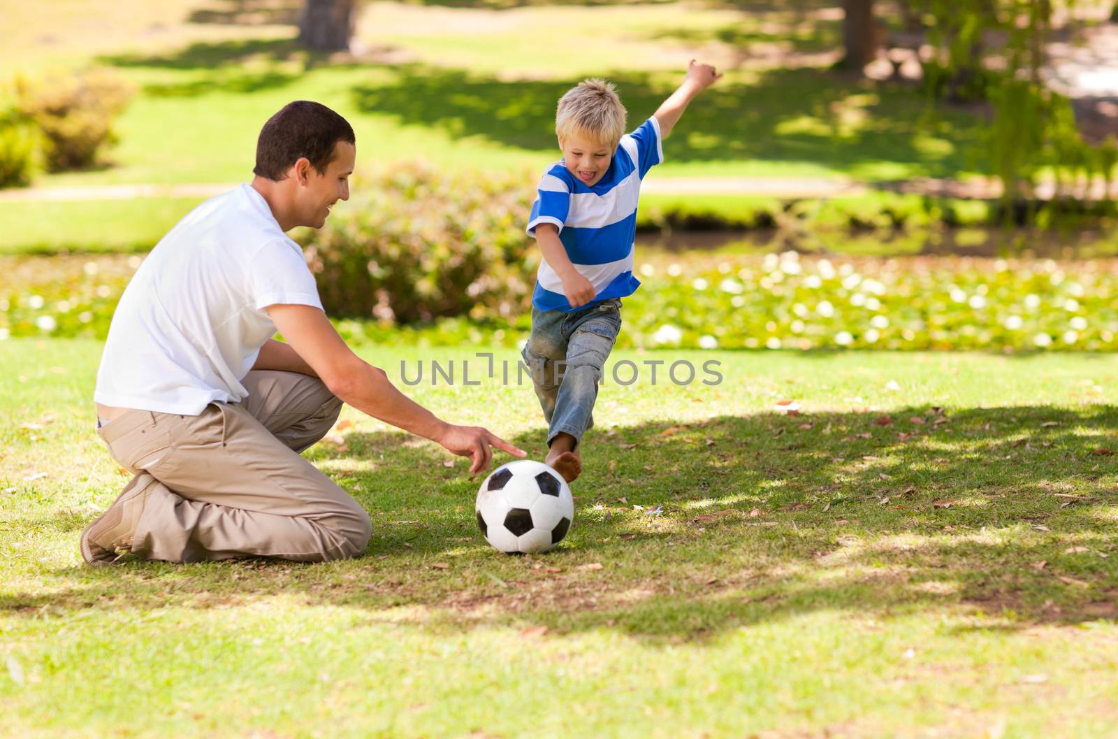 Father playing football with his son in a park by Wavebreakmedia