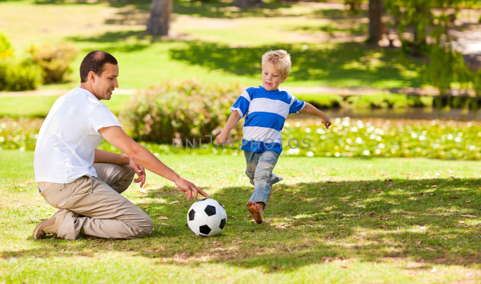 Father playing football with his son in a park by Wavebreakmedia