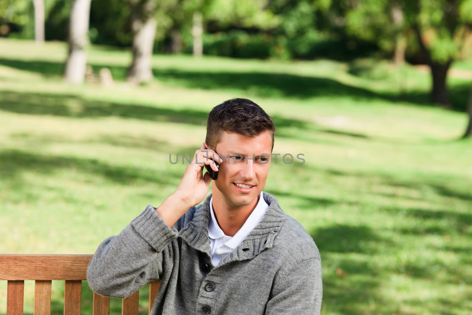 Young man phoning on the bench by Wavebreakmedia