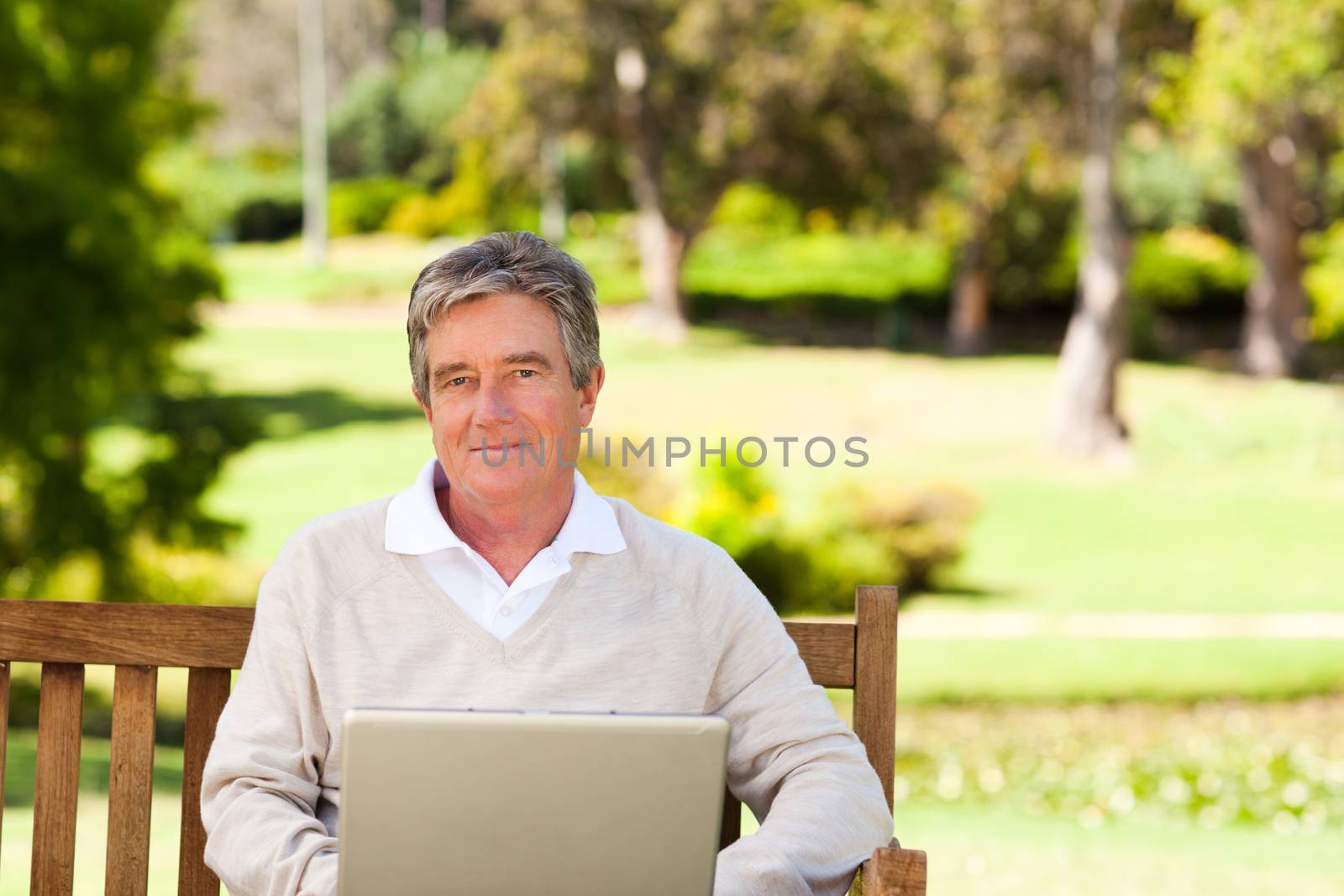 Senior man working on his laptop during the summer