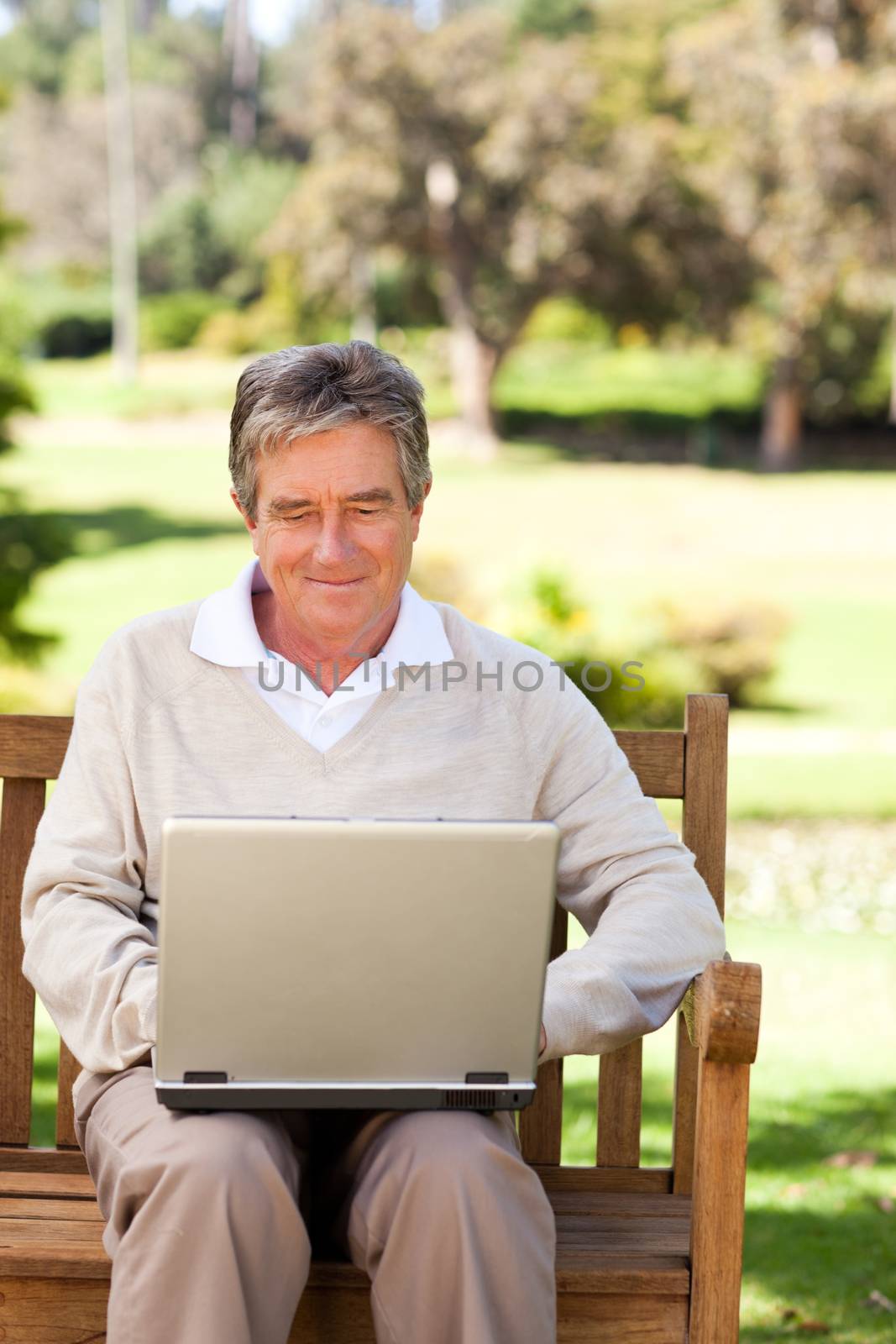 Senior man working on his laptop during the summer