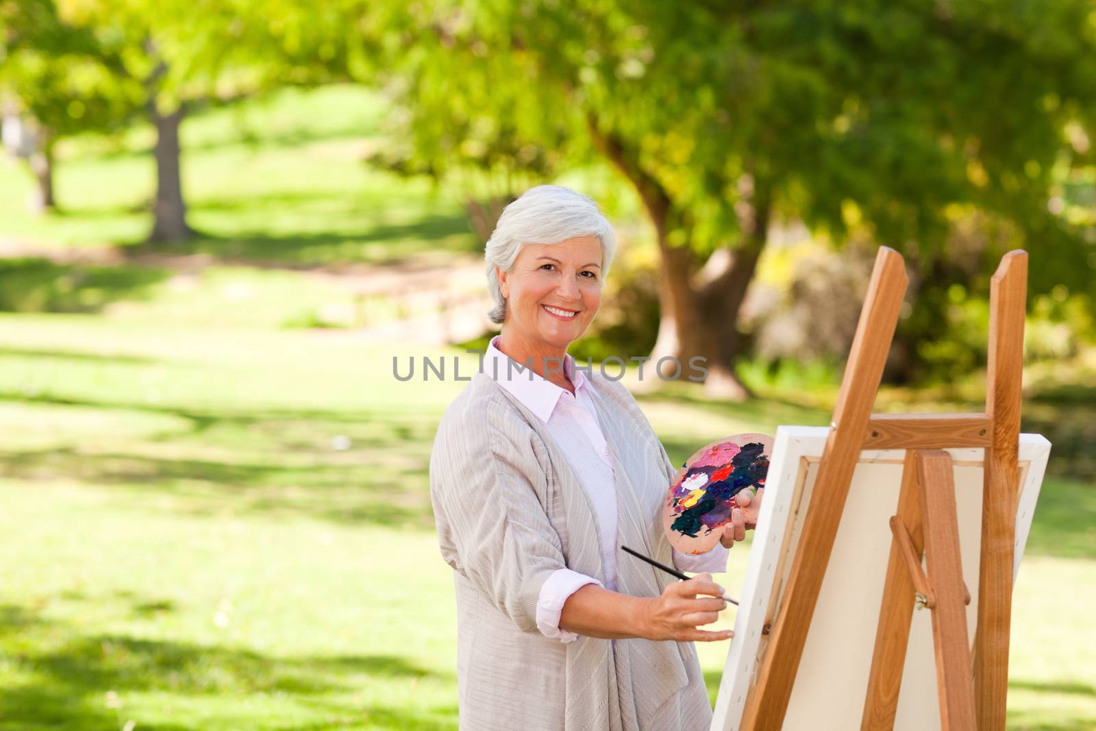 Senior woman painting in the park during the summer