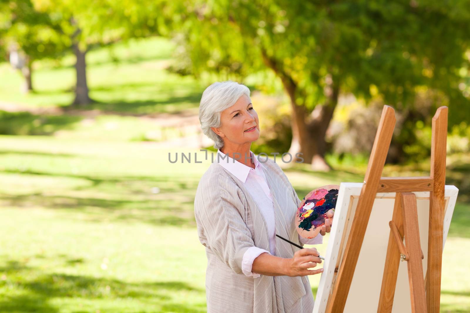 Senior woman painting in the park during the summer