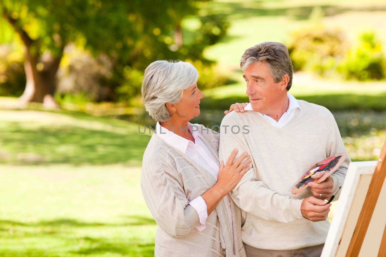 Retired couple painting in the park during the summer