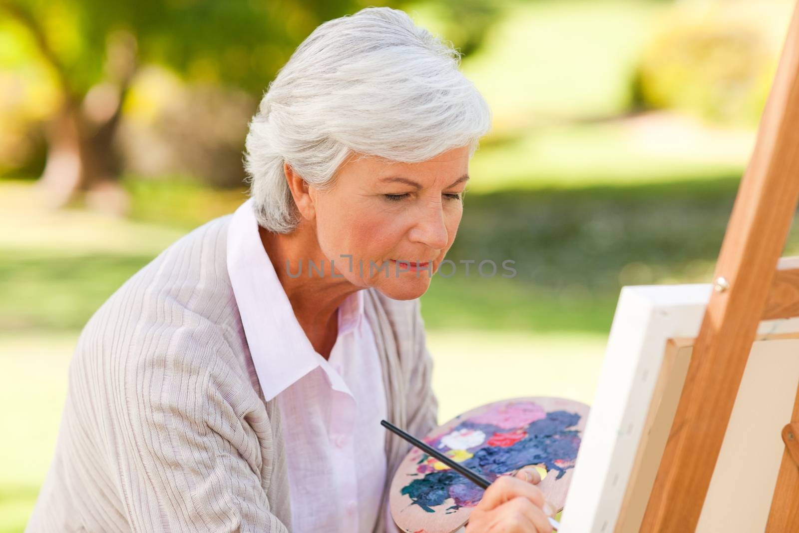 Mature woman painting in the park during the summer