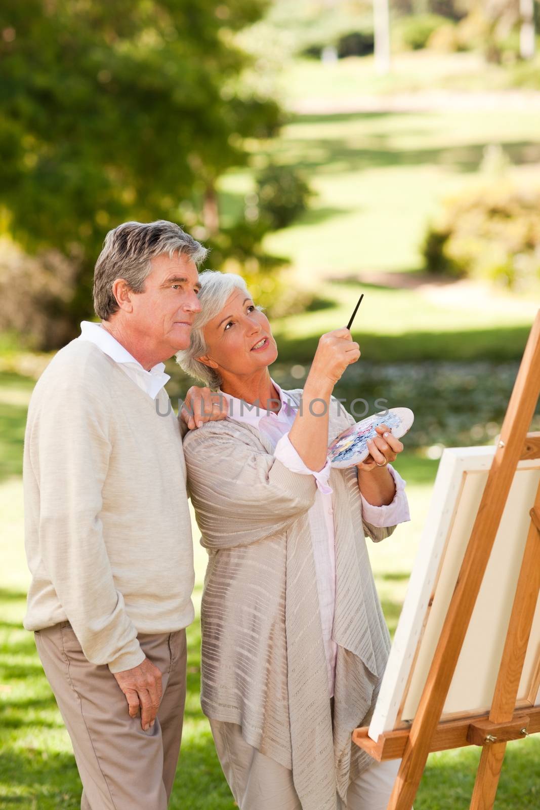Senior couple painting in the park during the summer