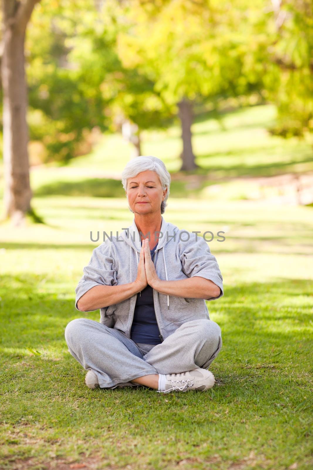 Senior woman practicing yoga in the park during the summer