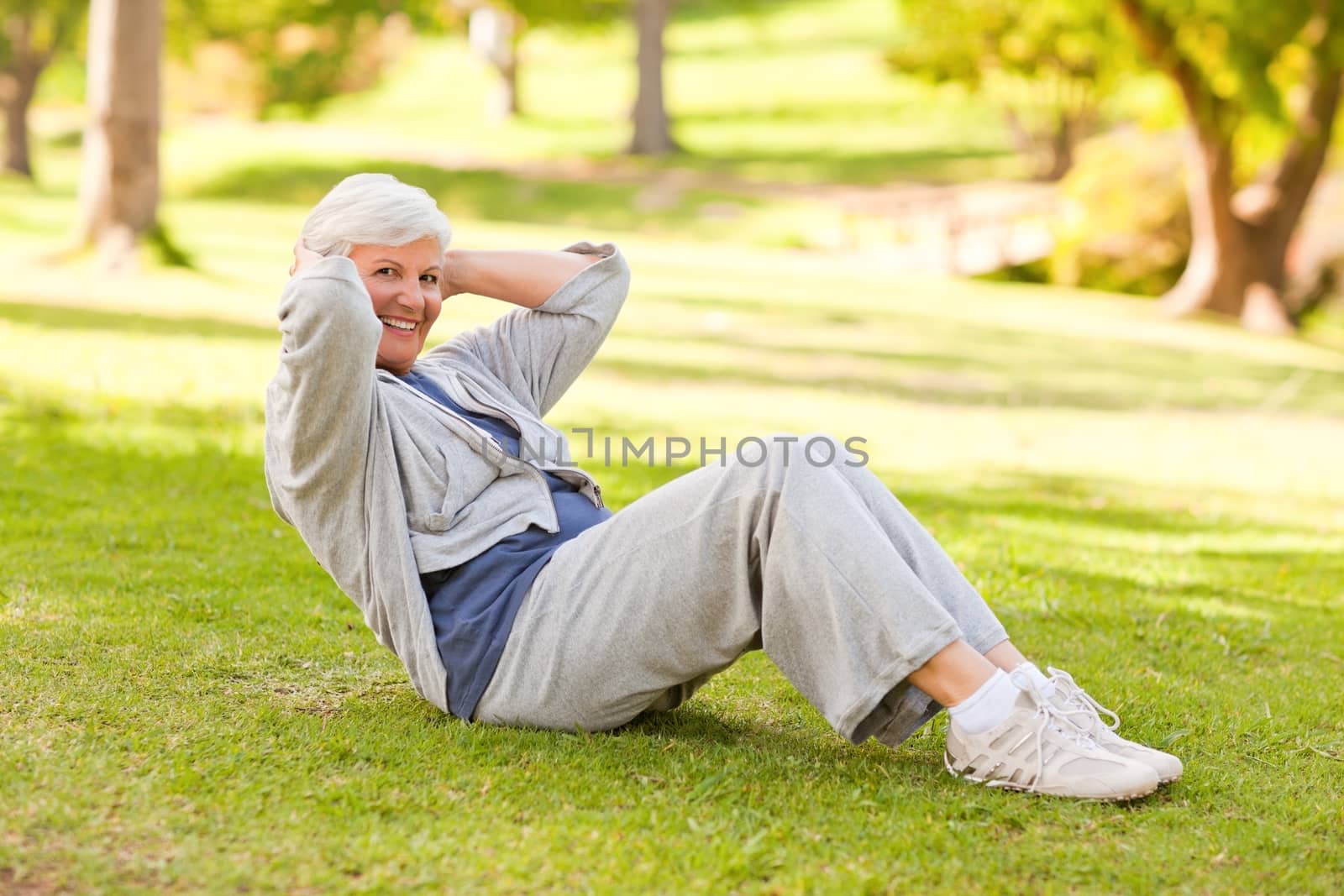 Retired woman doing her stretches in the park during the summer