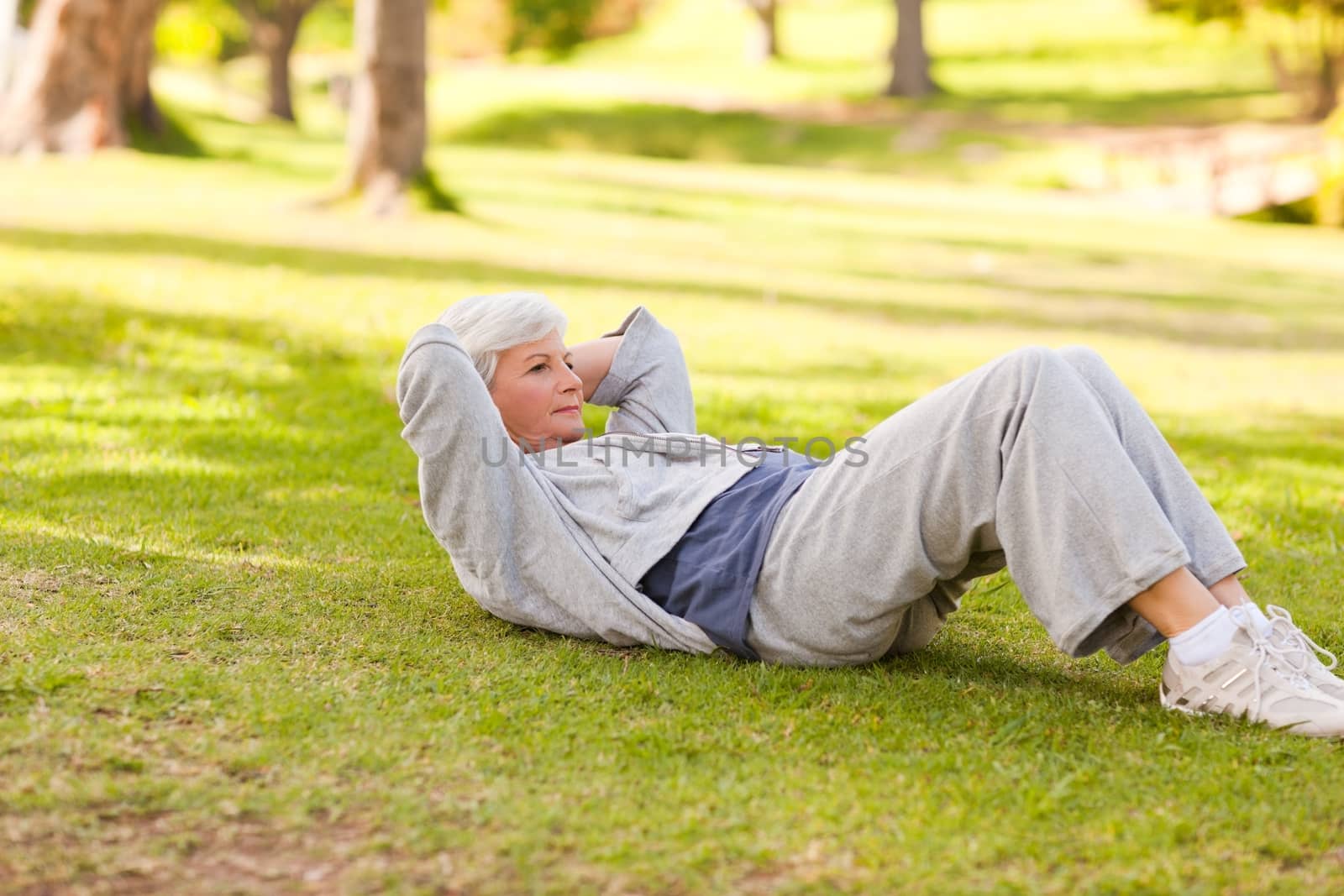 Retired woman doing her stretches in the park during the summer