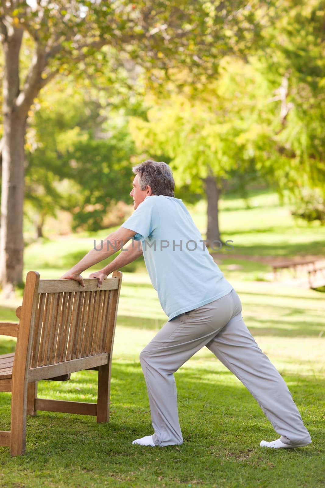 Retired man doing his stretches in the park during the summer