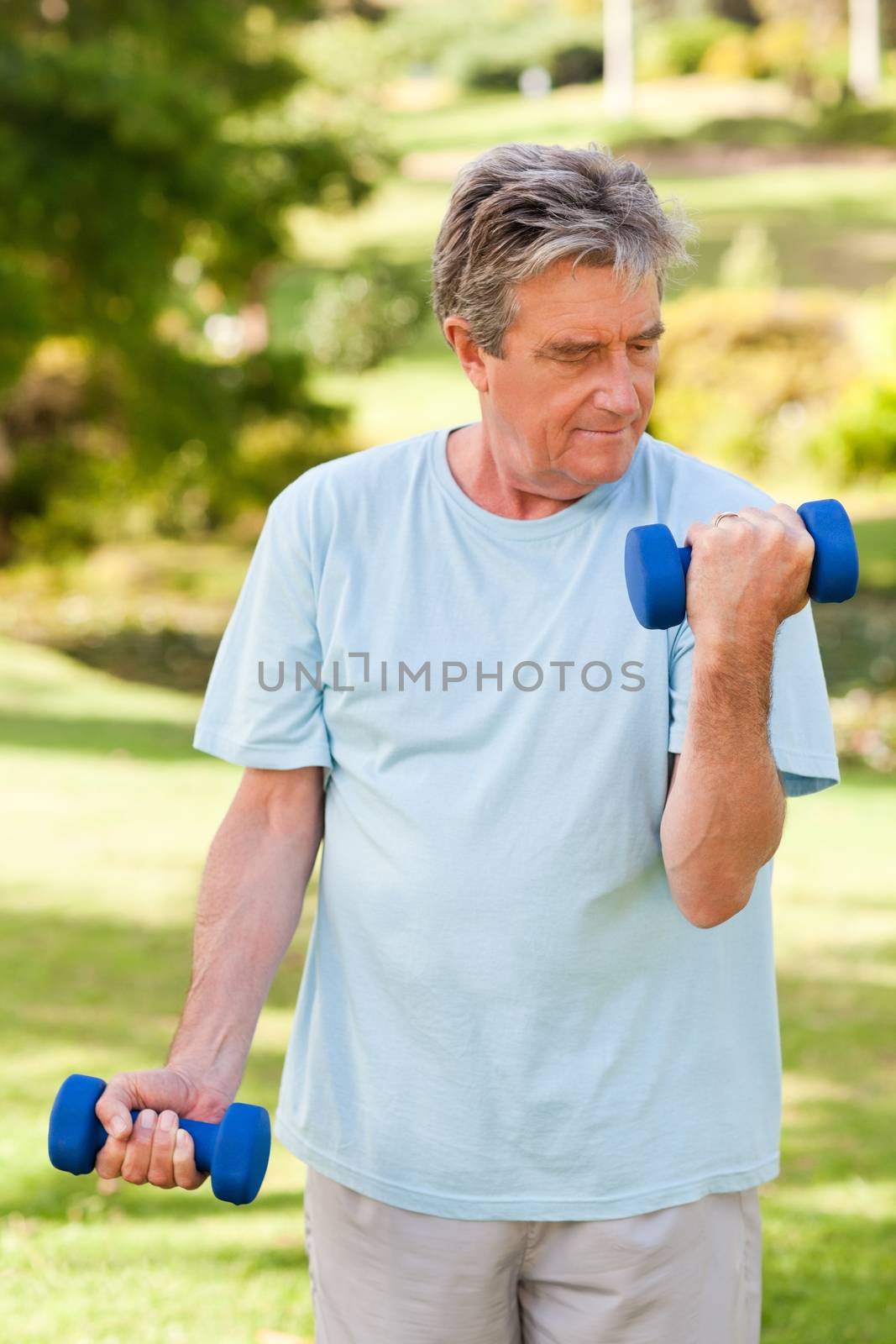 Elderly man doing his exercises in the park during the summer