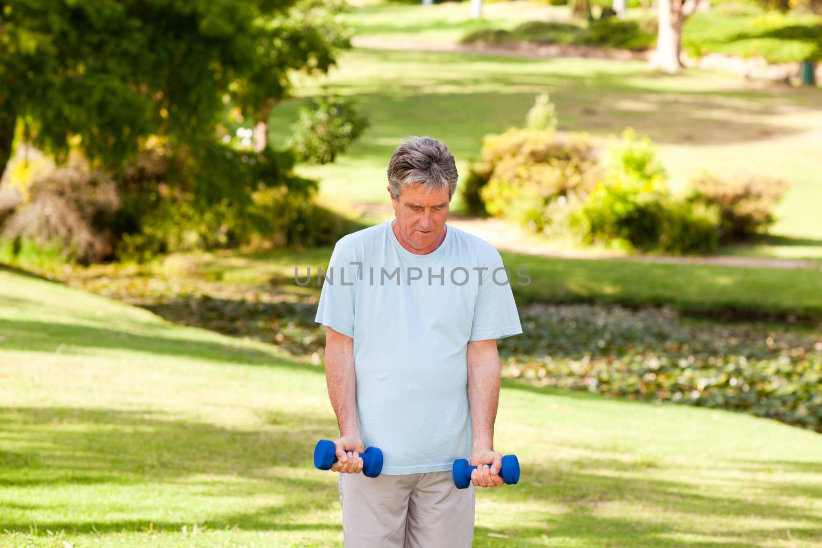 Mature man doing his exercises in the park during the summer