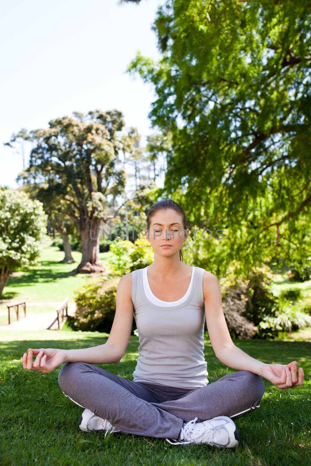 Young woman practicing yoga in the park during the summer