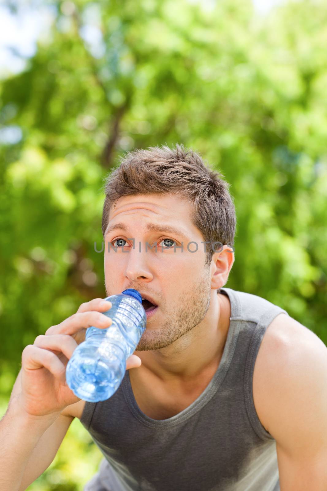 Sporty man drinking water in the park by Wavebreakmedia