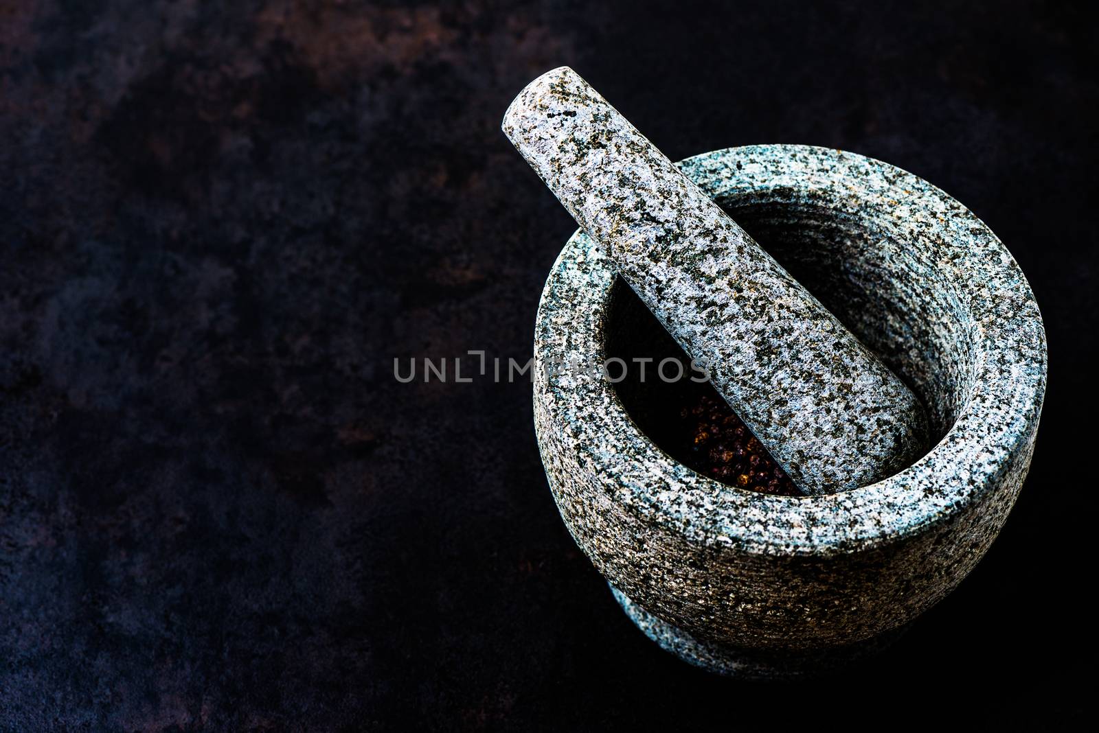 Mortar bowl and pestle on dark stone surface