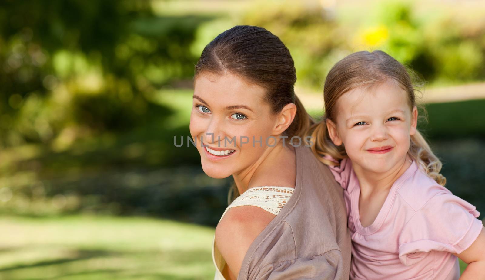 Beautiful mother giving daughter a piggyback during the summer