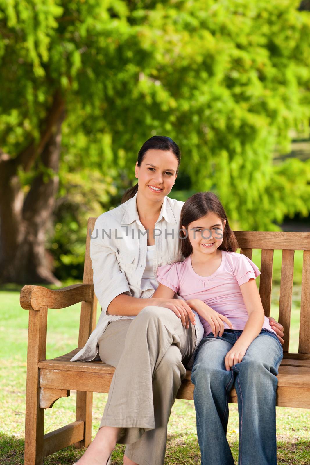 Mother and her daughter on the bench during the summer