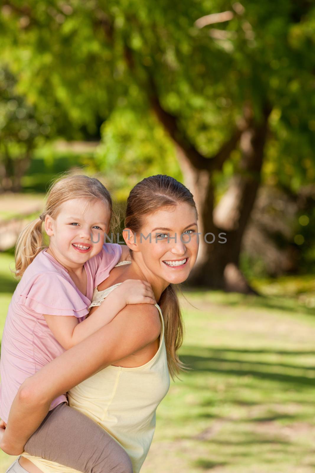 Beautiful mother giving daughter a piggyback by Wavebreakmedia