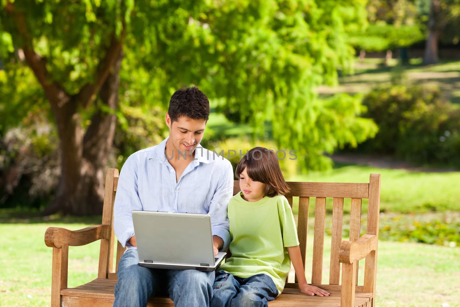 Son with his father looking at their laptop during the summer