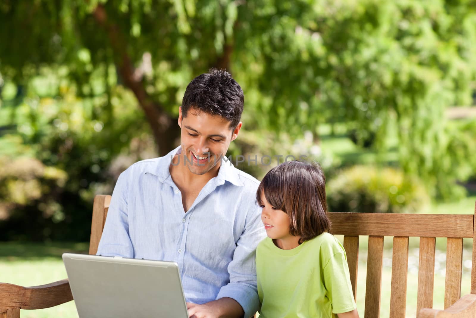 Father with his son looking at their laptop during the summer