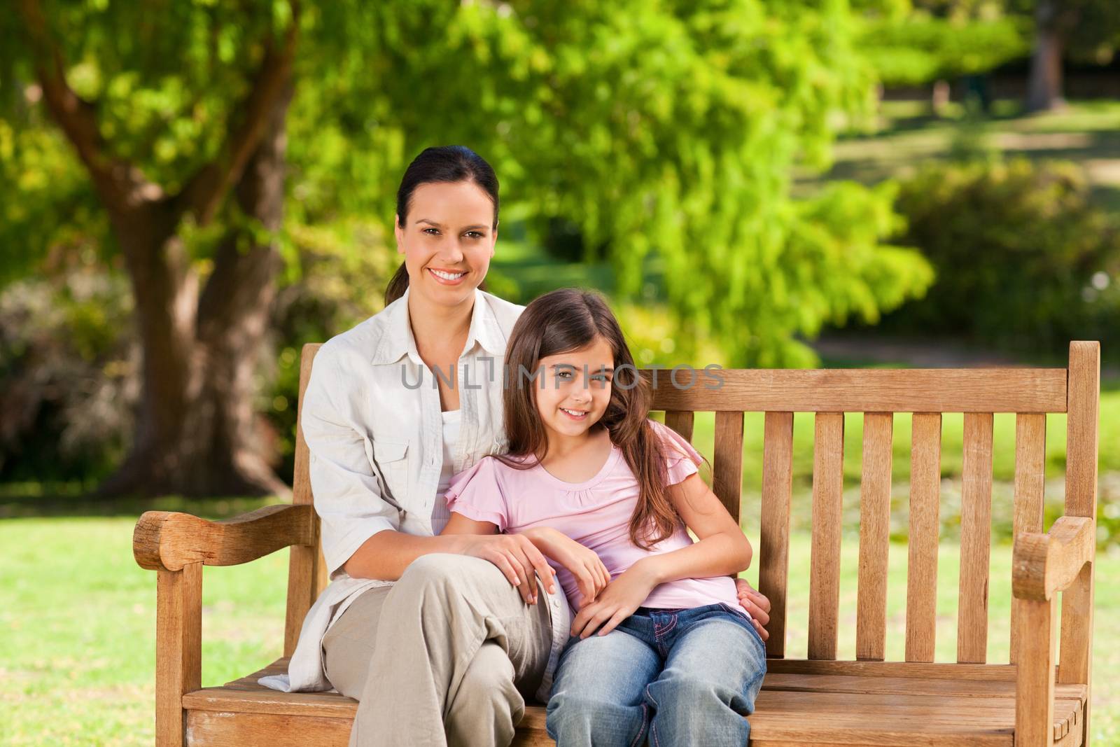 Mother and her daughter on the bench during the summer