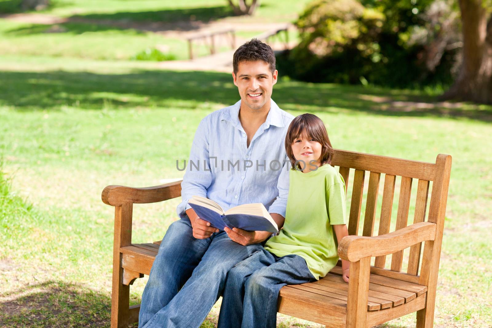 Son with his father reading a book during the summer