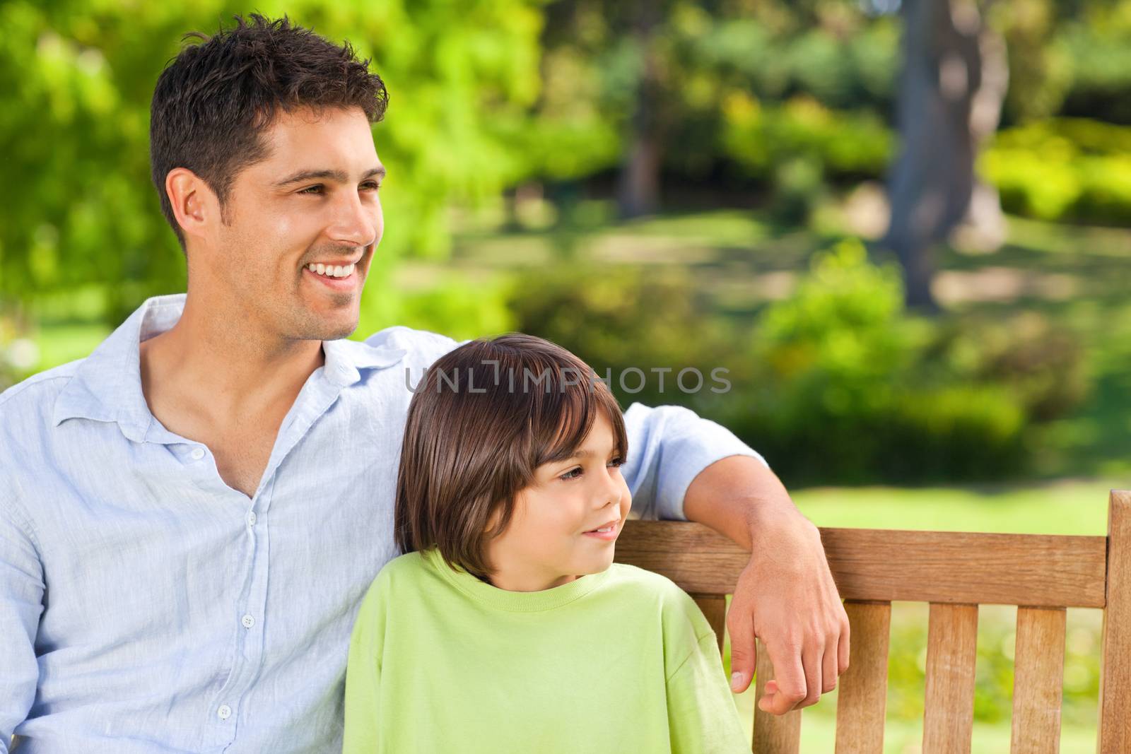 Son with his father on the bench during the summer