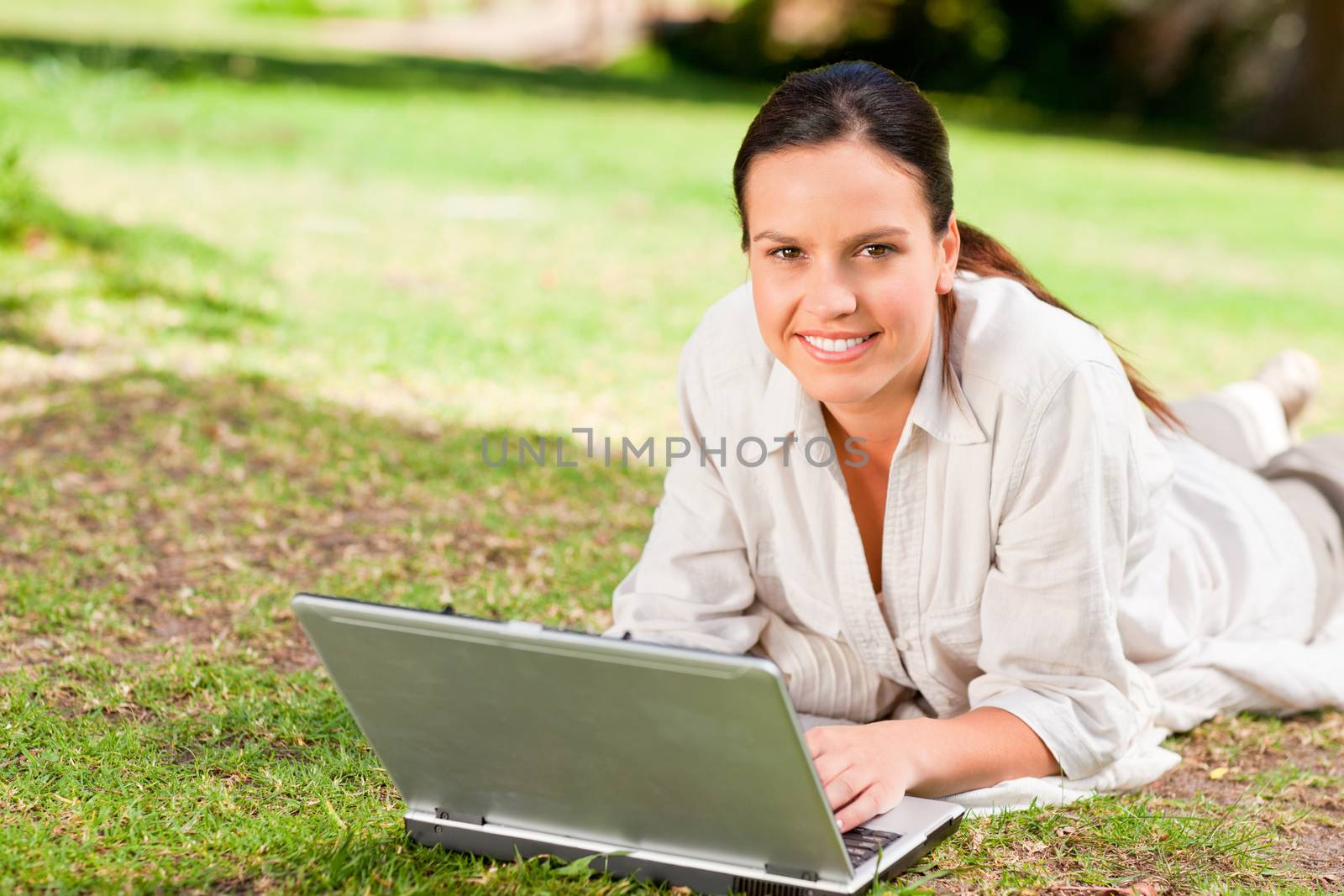 Woman working on her laptop in the park during the summer