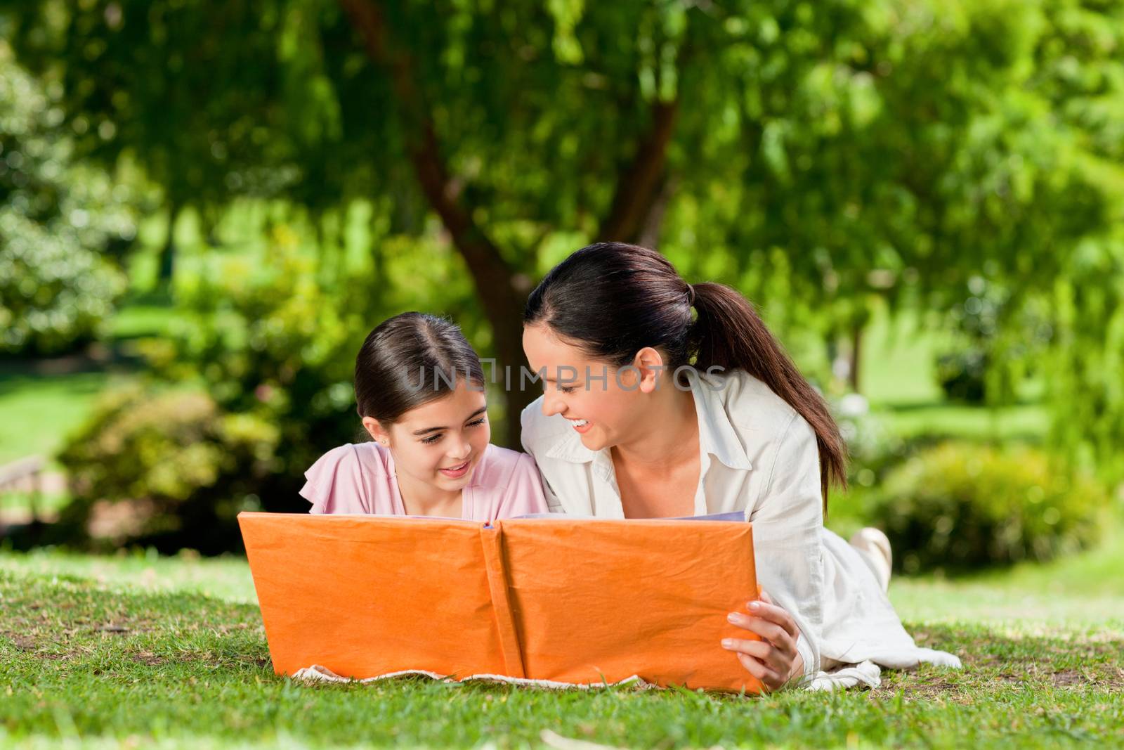 Mother and her daughter looking at their album photo during the summer