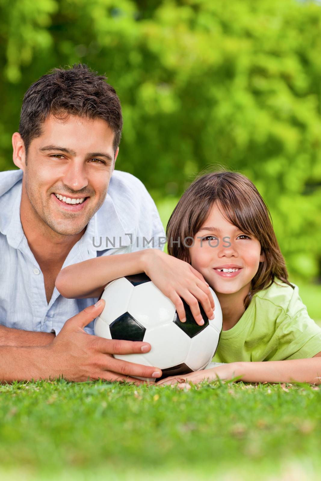 Father and his son with a soccer ball in the park during the summer