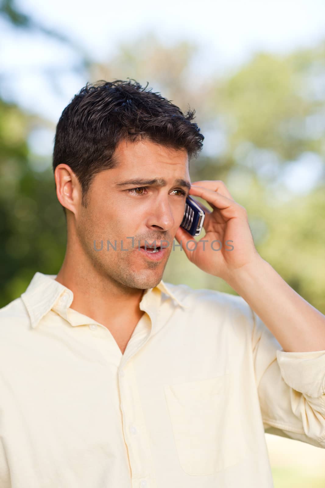Handsome man phoning in the park during the summer