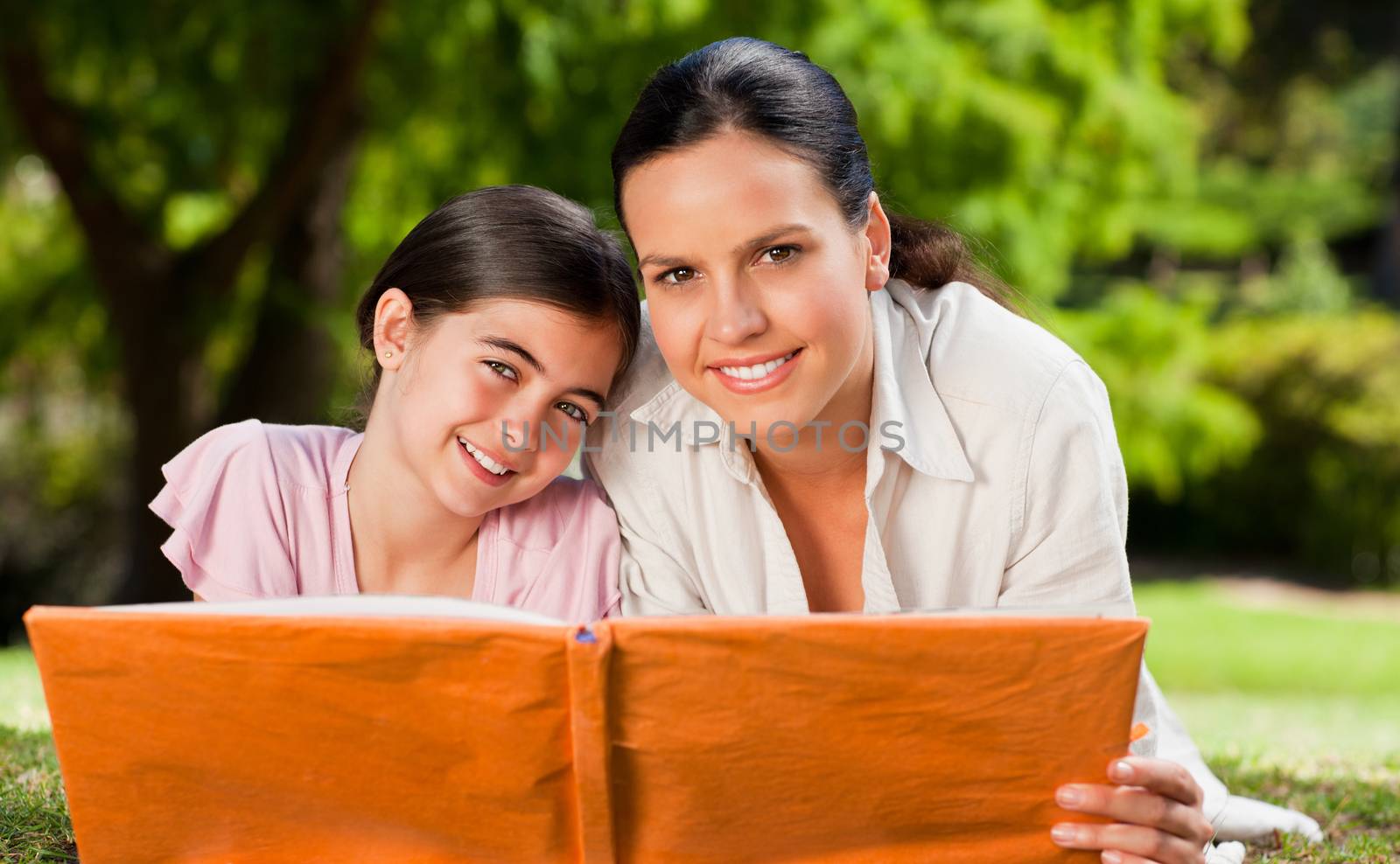 Mother and her daughter looking at their album photo during the summer