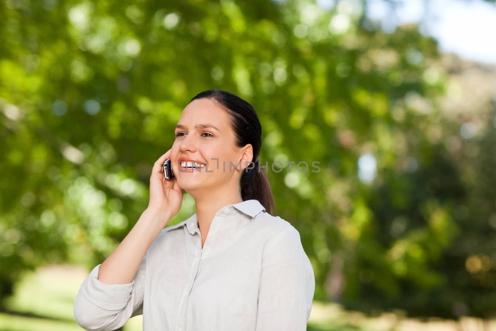 Young woman phoning in the park during the summer